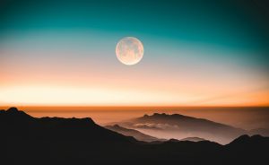 A full moon in the sky at sunrise